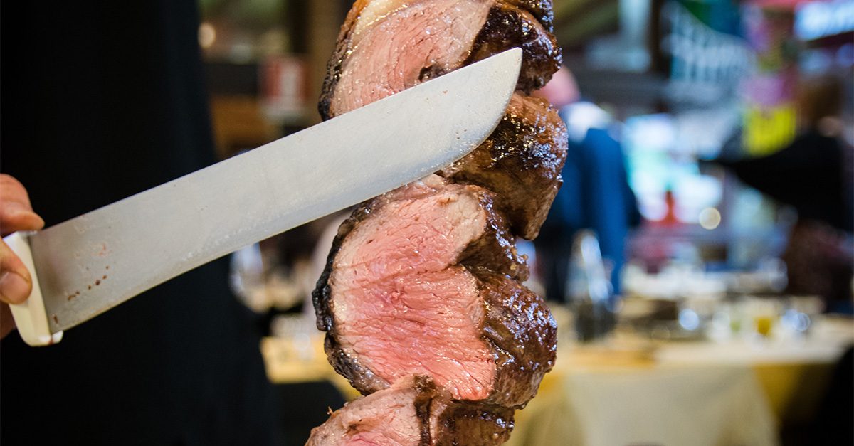 Waiter cutting beef picanha with large knife